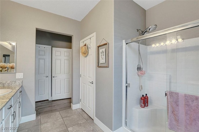 bathroom featuring vanity, tile patterned floors, baseboards, and a shower stall