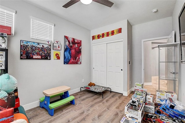 rec room with a ceiling fan, baseboards, and wood finished floors