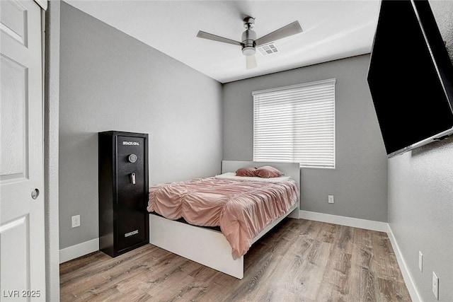 bedroom featuring baseboards, visible vents, and wood finished floors