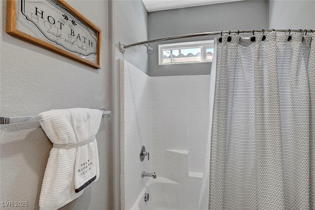 full bath with a textured wall and shower / tub combo with curtain