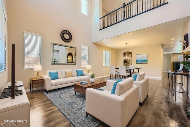 living room with baseboards, wood finished floors, and a towering ceiling