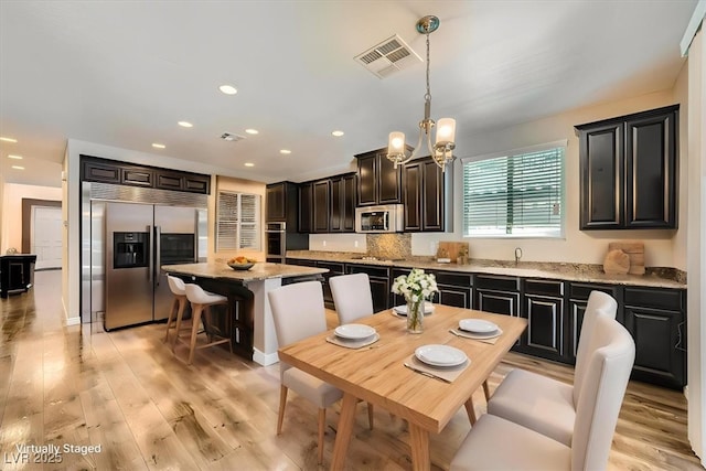 kitchen with visible vents, appliances with stainless steel finishes, a center island, an inviting chandelier, and recessed lighting