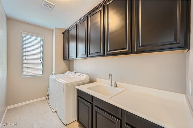 washroom featuring visible vents, cabinet space, a sink, baseboards, and separate washer and dryer
