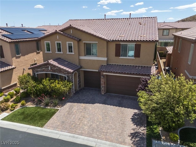 view of front of home with decorative driveway, a garage, stucco siding, and a tile roof