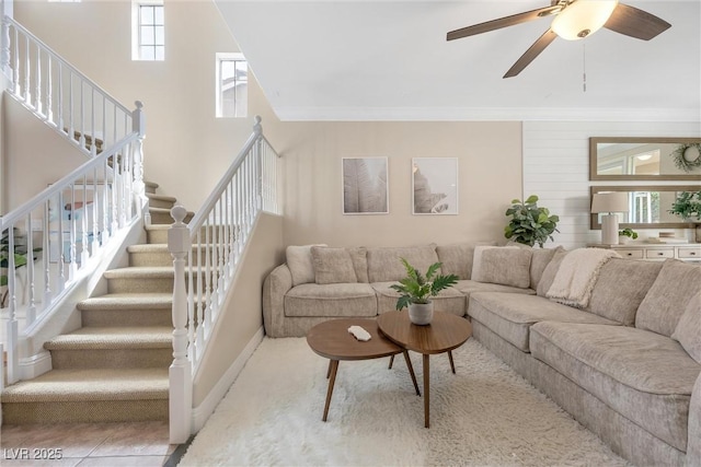 living room with stairs, ceiling fan, ornamental molding, and baseboards