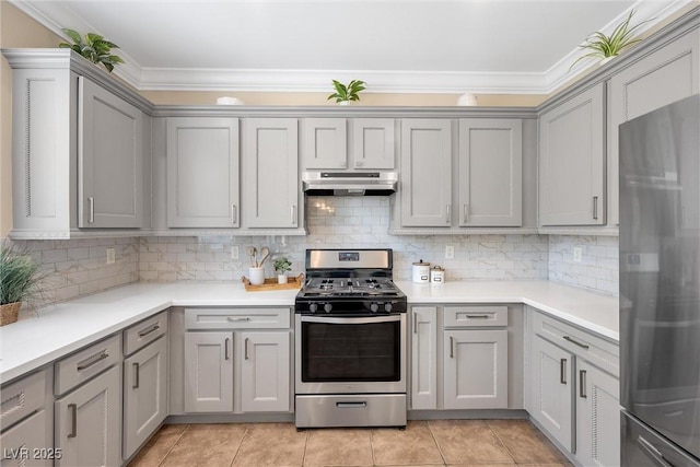 kitchen with crown molding, under cabinet range hood, gray cabinetry, and stainless steel appliances