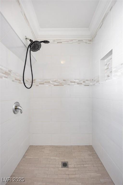 bathroom featuring a tile shower and ornamental molding