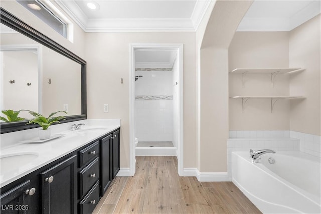 bathroom featuring double vanity, crown molding, a shower stall, wood finished floors, and a sink