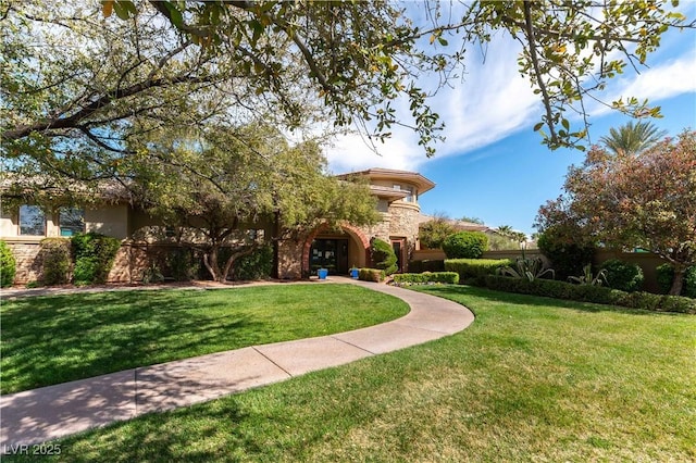 mediterranean / spanish house with stucco siding, stone siding, and a front yard