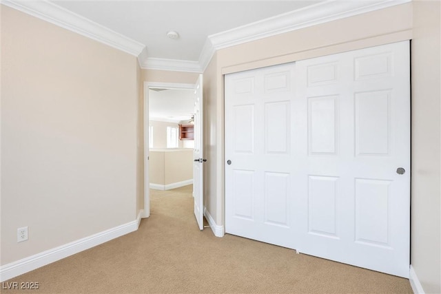 unfurnished bedroom with crown molding, baseboards, light carpet, and a closet