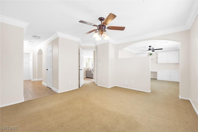 unfurnished living room with arched walkways, ceiling fan, light colored carpet, and ornamental molding