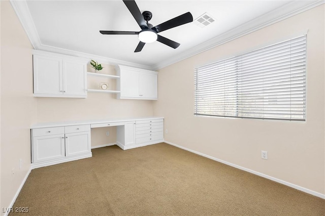 unfurnished office featuring crown molding, ceiling fan, light carpet, built in study area, and visible vents