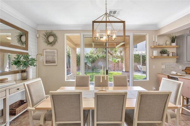 tiled dining area with crown molding and a notable chandelier