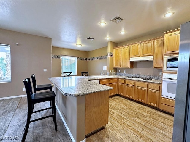 5704 Burdel St, Las Vegas, NV 89149 - kitchen featuring a peninsula, under cabinet range hood, white appliances, and visible vents