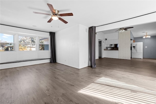 unfurnished living room featuring ceiling fan with notable chandelier and wood finished floors