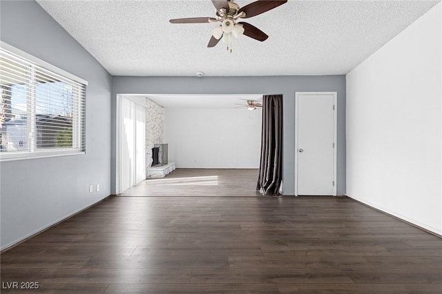 unfurnished living room with a stone fireplace, a ceiling fan, and a textured ceiling