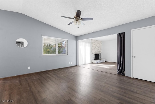 unfurnished living room with a ceiling fan, a stone fireplace, wood finished floors, and lofted ceiling