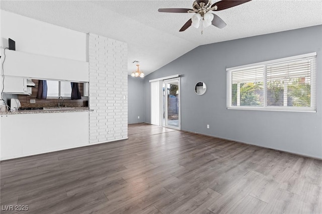 unfurnished living room featuring a textured ceiling, ceiling fan with notable chandelier, wood finished floors, and vaulted ceiling