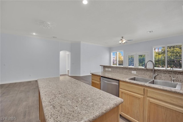 kitchen featuring a sink, arched walkways, open floor plan, and dishwasher