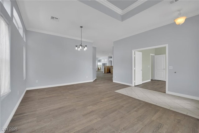 unfurnished living room with visible vents, ornamental molding, an inviting chandelier, wood finished floors, and baseboards