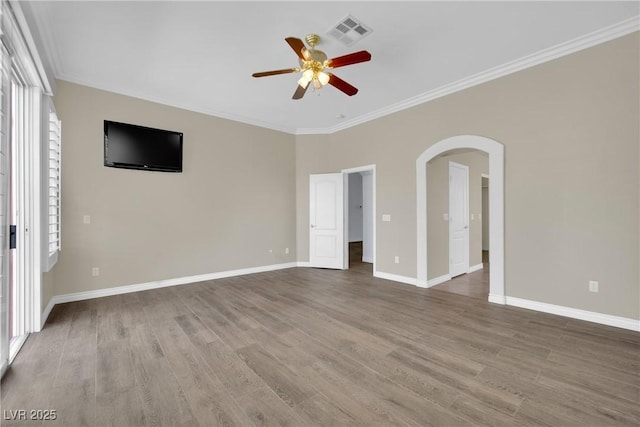 unfurnished bedroom featuring arched walkways, baseboards, wood finished floors, visible vents, and ornamental molding