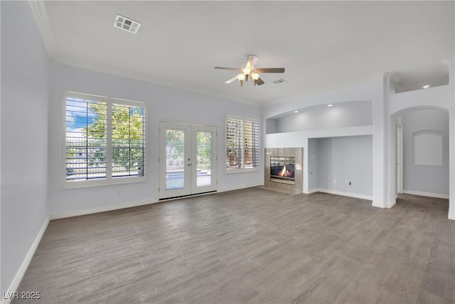 unfurnished living room with baseboards, arched walkways, ceiling fan, and a wealth of natural light