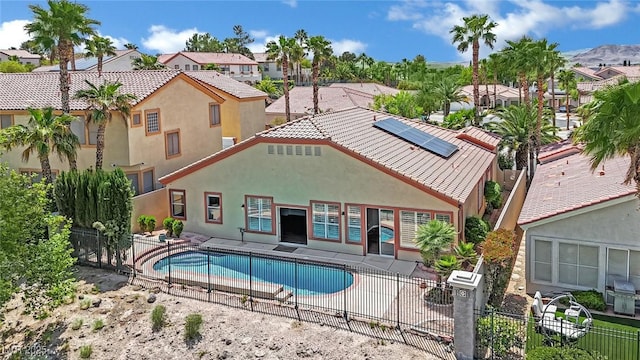 back of property featuring fence private yard, stucco siding, a fenced in pool, a residential view, and solar panels