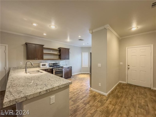 kitchen featuring stainless steel gas stove, a sink, ornamental molding, wood finished floors, and dark brown cabinets