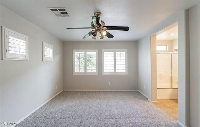 empty room featuring a ceiling fan, light carpet, and baseboards
