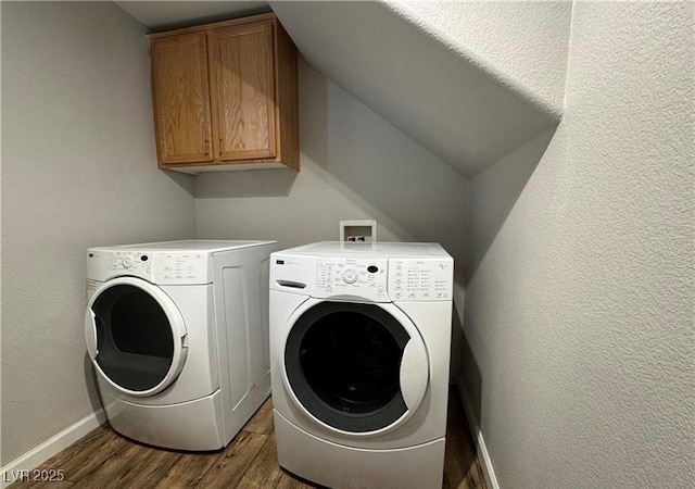 laundry room with cabinet space, washing machine and dryer, dark wood finished floors, and baseboards