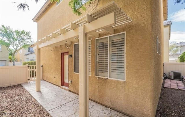 view of side of property with a patio area, fence, stucco siding, and central AC