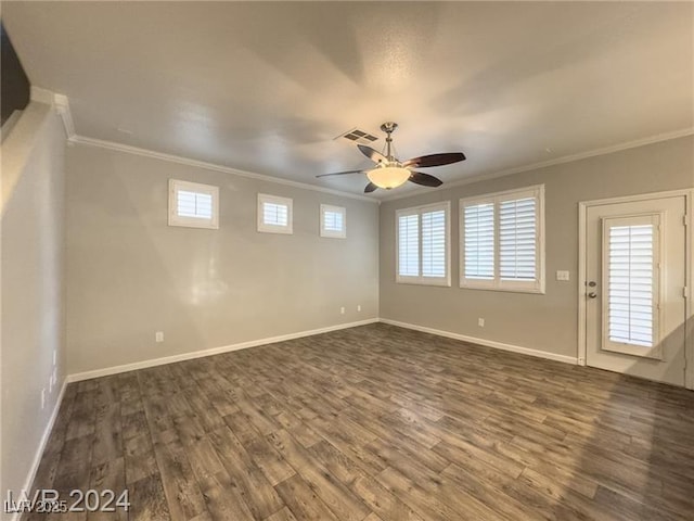 empty room featuring ceiling fan, crown molding, dark wood-type flooring, and baseboards