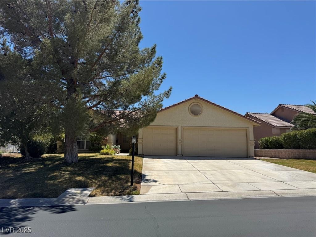 ranch-style house with an attached garage, driveway, a tile roof, and stucco siding