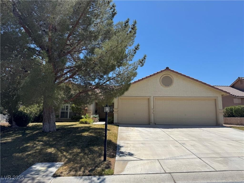 ranch-style house featuring an attached garage, stucco siding, a tiled roof, and concrete driveway