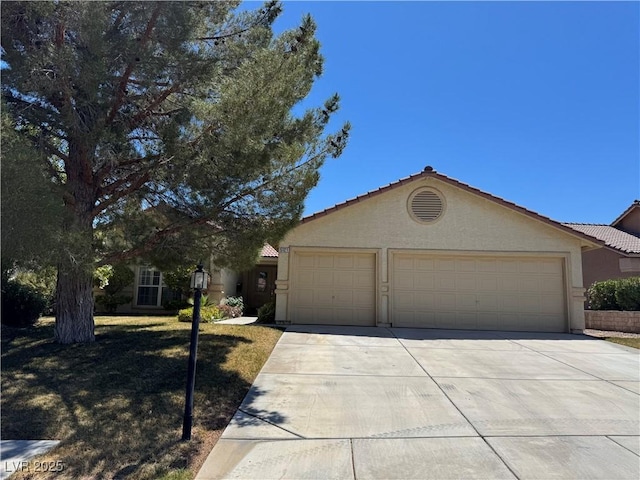 ranch-style house featuring concrete driveway, a tiled roof, stucco siding, and a garage