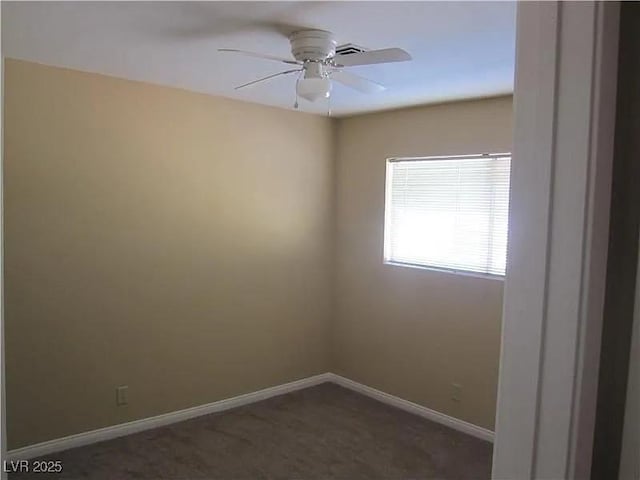 unfurnished room with a ceiling fan, baseboards, and dark colored carpet