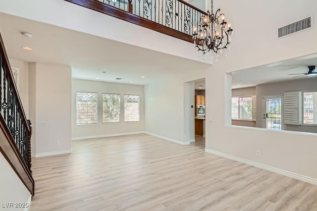 unfurnished living room featuring light wood-type flooring, healthy amount of natural light, stairway, and recessed lighting