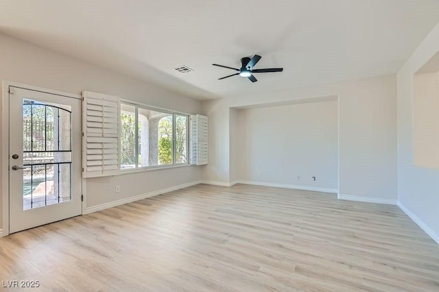 spare room featuring ceiling fan, light wood finished floors, and baseboards