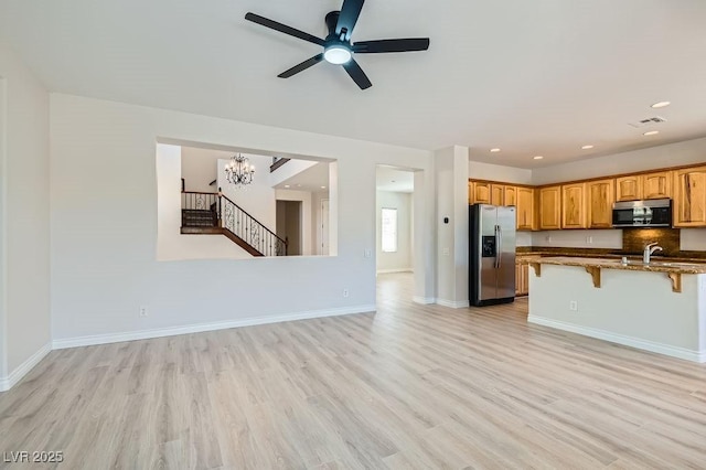 kitchen with stainless steel appliances, a breakfast bar area, light wood finished floors, a chandelier, and recessed lighting