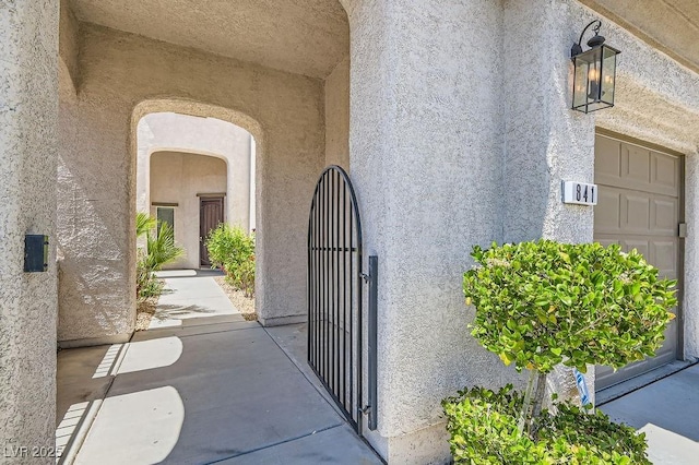 view of exterior entry featuring stucco siding and a gate