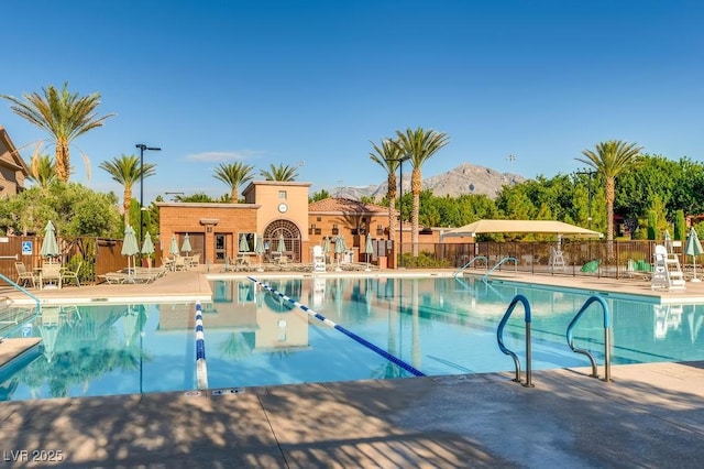 community pool with a mountain view, a patio area, and fence