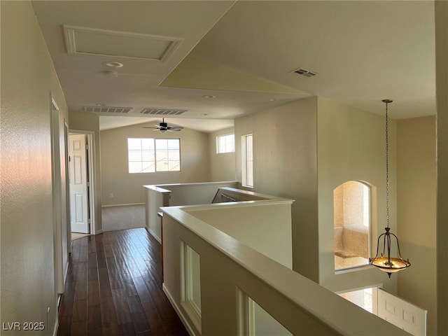 hall with baseboards, visible vents, vaulted ceiling, an upstairs landing, and dark wood-style floors