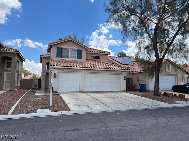 mediterranean / spanish-style house with a tiled roof, stucco siding, driveway, and solar panels