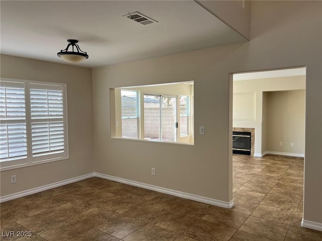 empty room featuring a wealth of natural light, baseboards, and visible vents