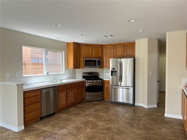 kitchen featuring brown cabinets, light countertops, appliances with stainless steel finishes, and visible vents