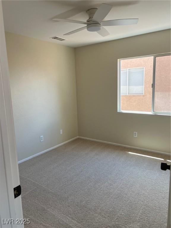 unfurnished room with carpet, visible vents, baseboards, and ceiling fan