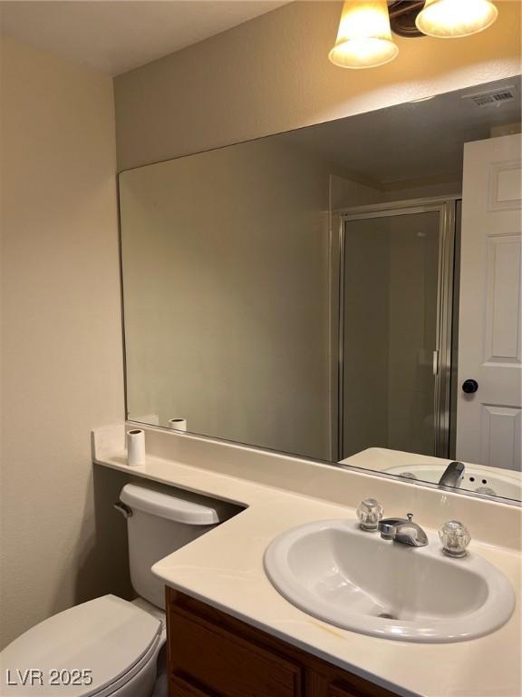 bathroom featuring vanity, toilet, a shower stall, and visible vents