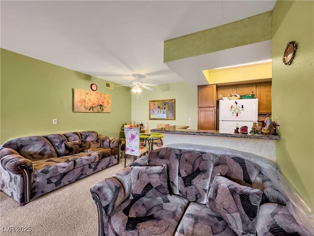 carpeted living area featuring visible vents and a ceiling fan
