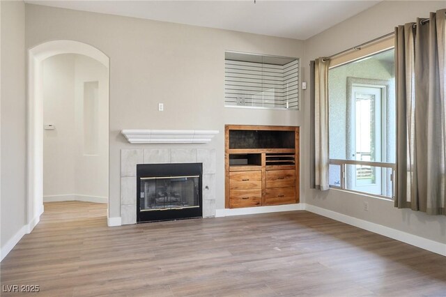 3278 Turning Bridge St, Las Vegas, NV 89135 - unfurnished living room with a tiled fireplace, baseboards, and wood finished floors