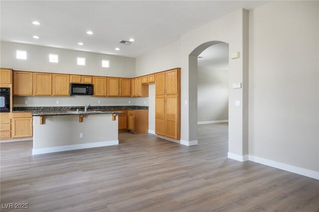 3278 Turning Bridge St, Las Vegas, NV 89135 - kitchen with arched walkways, recessed lighting, baseboards, light wood-type flooring, and black appliances